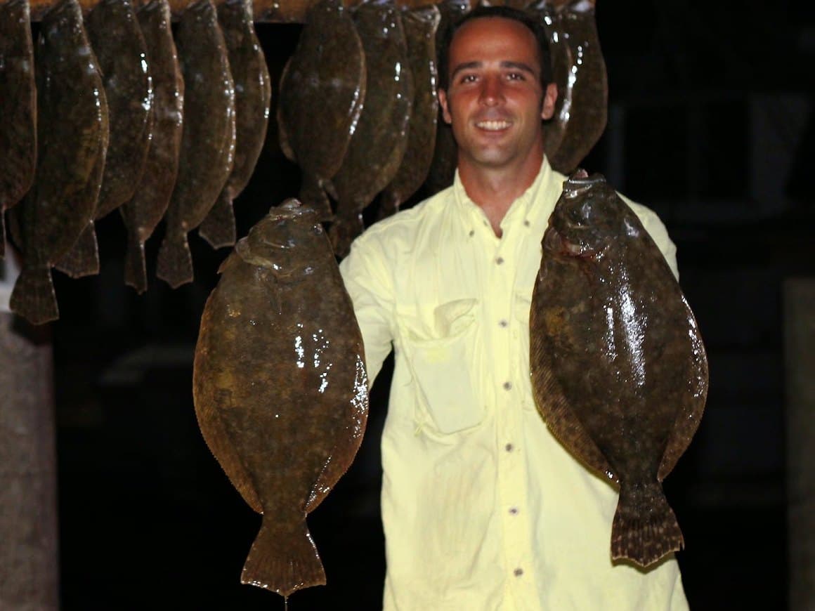 Angler holding up two big flounder in front of a full stringer at Port O'Connor