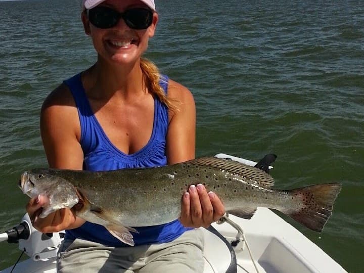 Angler on a bay boat holding a big speckled trout